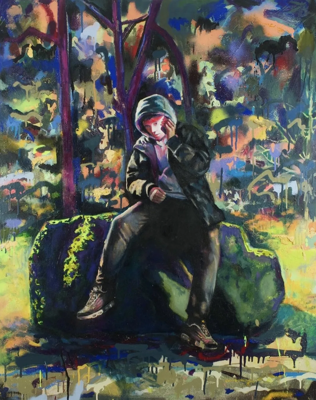 A hooded figure seated on a rock in woodland