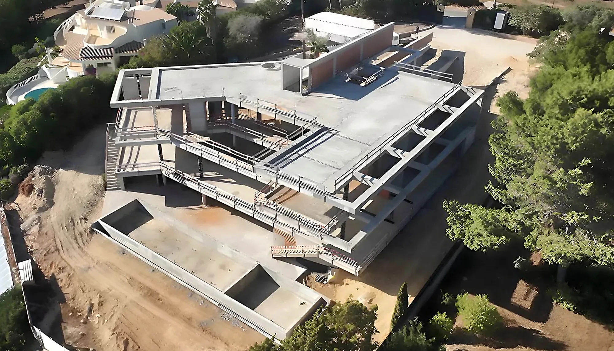 The house under construction, seen from above as a concrete shell on the headland