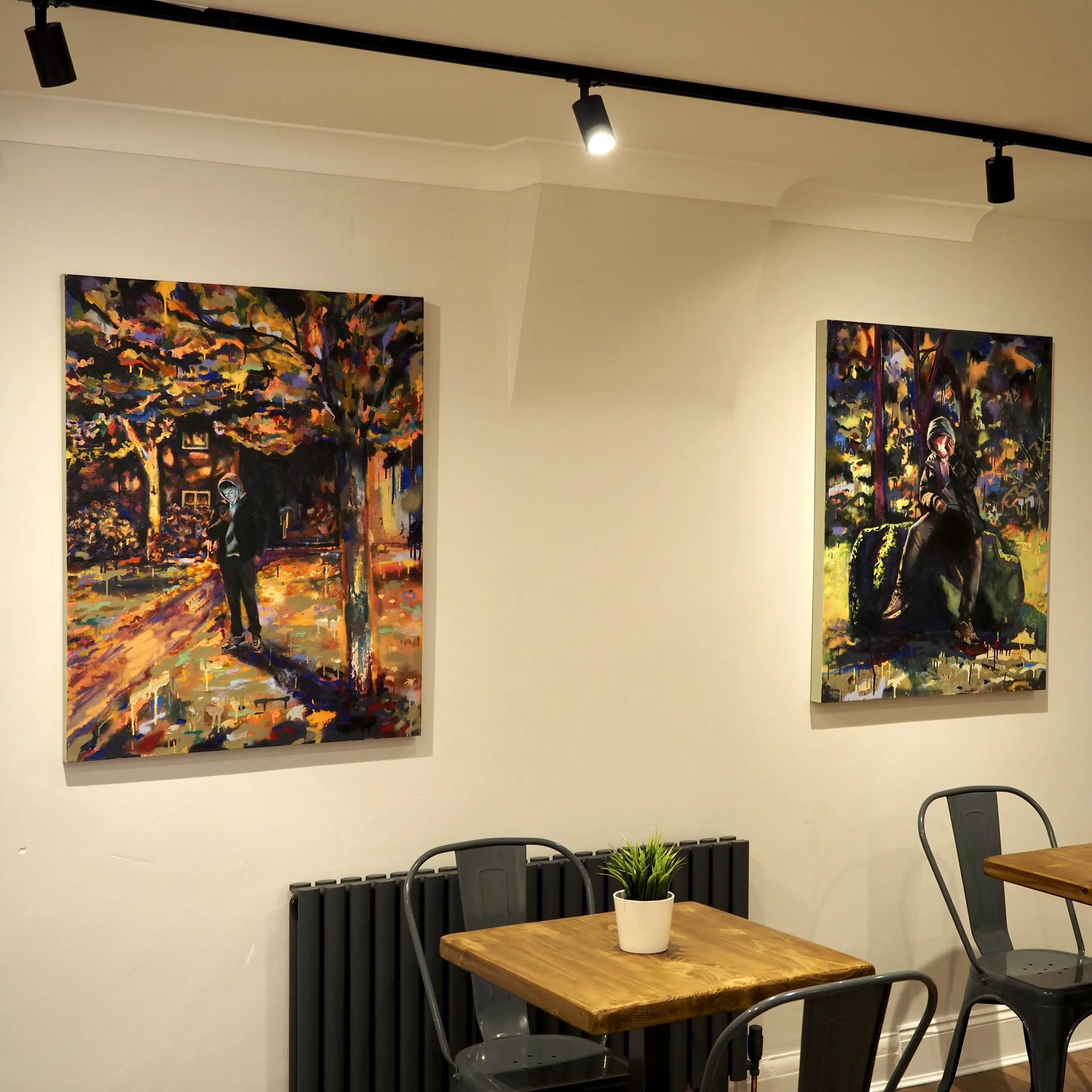 Two figurative paintings hung on the long wall above the tables